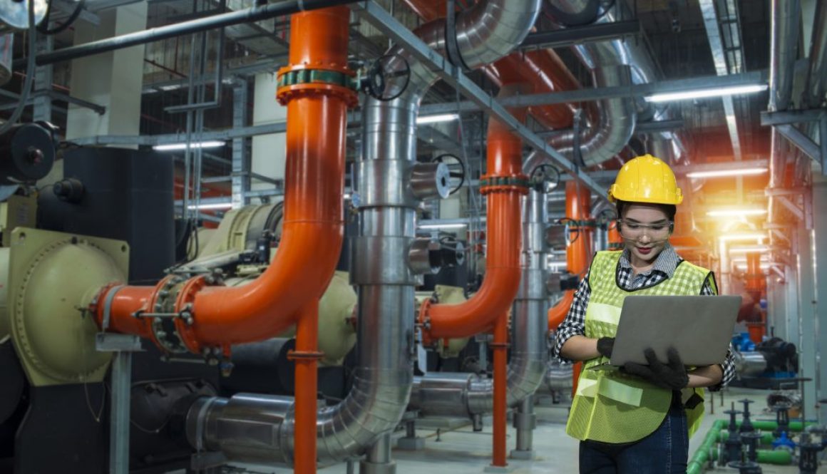 industrial plant in factory, women worker using laptop on chiller water cool in plant room background.