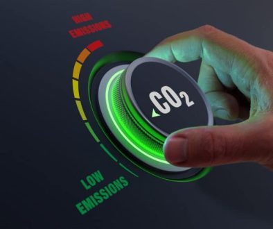 Lower CO2 Emissions To Limit Global Warming And Climate Change. Concept With Manager Hand Turning Knob To Reduce Levels Of CO2. New Technology To Decarbonize Industry, Energy And Transport